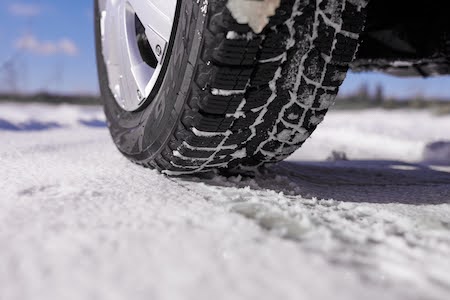 Car tires on winter snow road close up