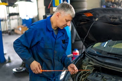 Fairfax auto mechanic checking a car’s oil levels